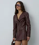 Campera de mujer confeccionada en material sintético tipo PU, con diseño de cuello solapa, hombreras estructuradas y cierre frontal asimétrico con cremallera. Presenta un corte regular y mangas largas.