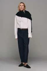 Pantalón chino de tiro bajo color marrón oscuro, con pernera recta y bajo con vuelta. Incluye un cinturón trenzado delgado de color marrón claro. Cuenta con bolsillos delanteros y cierre frontal con cremallera y botón.