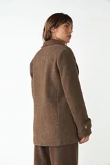 Abrigo de cuello sastre color beige, con forro, cierre frontal con botones, bolsillos con solapa y presillas en mangas. Confeccionado en lana fina sin teñir, diseñado exclusivamente por Don Baez.