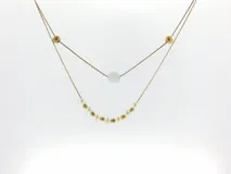 Collar doble con cordones finos, cuentas doradas, perlas sintéticas y cuenta central translúcida.