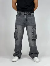 Pantalón de jean gris oscuro lavado, estilo cargo y corte baggy, con múltiples bolsillos laterales y calce holgado.