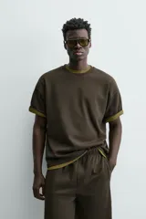 Sudadera de manga corta con cuello redondo, confeccionada en tejido texturizado de color verde oscuro/marrón. Presenta un corte relajado (relaxed fit).