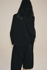 Blazer cruzado Zara de color negro, con cuello de solapa, manga larga y bolsillos laterales ocultos en la costura. Cuenta con cierre frontal de botones.