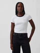 Remera corta de ajuste ceñido color blanco con cuello redondo y ribete negro. Presenta mangas cortas y el logo bordado de Gap en el pecho.