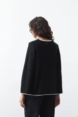 Sweater de tejido de punto con silueta recta y calce relajado. Presenta un diseño liso en color negro con detalles de vivos en contraste color blanco en el cuello redondo, los puños y el ruedo.