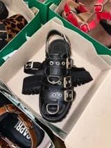 Sandalias negras de cuero vacuno con suela track y múltiples hebillas plateadas.