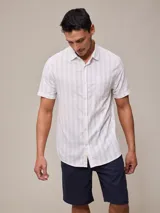 Camisa de manga corta para hombre, color blanco con rayas verticales finas en relieve. Tiene cuello abotonado, bolsillo en el pecho izquierdo y logo bordado pequeño.