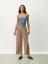 Pantalón de vestir color tostado de corte ancho y relajado, tiro alto con trabillas para cinturón, pinzas frontales y bolsillos laterales.