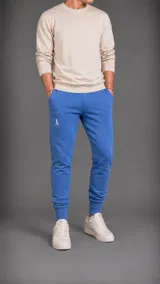 Pantalón tipo jogger de color azul, con cintura elástica, puños acanalados en los tobillos y logo bordado pequeño en la parte superior del muslo.
