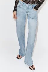 Jeans de tiro bajo con diseño wide leg y corte full length. Presenta cinco bolsillos, cierre frontal con cremallera y botón metálico, en un lavado de denim claro.