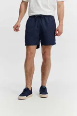 Short de baño azul, de corte clásico y largo corto, con cintura elástica y cordón ajustable bicolor. Cuenta con bolsillos laterales y uno trasero.