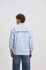 Camisa de manga larga con diseño a rayas verticales en color verde y blanco, cuello clásico y estampa con bordado en la espalda con la frase "Expect Nothing, appreciate everything".