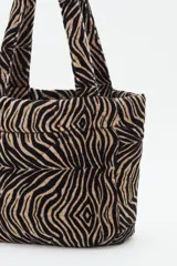 Cartera tipo mini tote con estampado animal print de cebra, confeccionada en algodón con relleno acolchado y doble asa de mano.