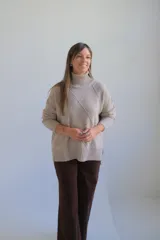 Polerón de cuello alto con diseño de rombos tejidos en relieve, mangas largas con puños acanalados y ruedo también acanalado.