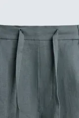 Bermuda de lino color blanco hueso, de corte relajado y tiro medio. Presenta cintura elástica ajustable con cordón, pliegues frontales y bolsillos laterales y trasero.