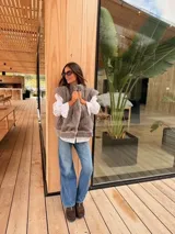 Chaleco de piel sintética en color gris, con diseño reversible. El interior presenta un forro de tela color mostaza con estampado floral bordado. Posee un corte holgado y sin mangas.