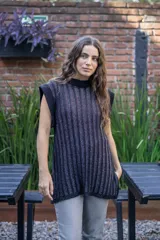 Chaleco tejido de punto acanalado vertical en color negro con hilos de lurex plateados. Presenta cuello redondo, hombros amplios con efecto de hombrera caída y tajos laterales en el ruedo.