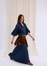Camisa de jean azul con cuello mao, cierre frontal con botones y mangas tres cuartos abullonadas con puños elásticos.