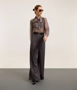 Pantalón de sastrería de corte recto y tiro alto, con diseño de pierna ancha, trabillas en la cintura, cierre frontal con botón y cremallera, y bolsillos laterales con costuras verticales.