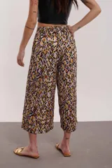Pantalón capri de tiro alto con estampado abstracto en tonos lila, negro, naranja y amarillo.