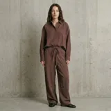 Camisa de corte oversize y textura rústica, con cuello clásico, cierre frontal de botones y manga larga con puños abotonados.