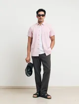 Camisa azul de manga corta, con cuello abotonado y bolsillo en el pecho.