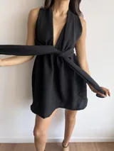 Vestido corto negro con escote halter y espalda descubierta. Presenta un corte a la cintura con falda acampanada.