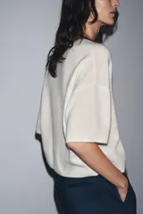 Jersey de punto color crema, confeccionado en 100% lana, con cuello redondo y mangas cortas anchas, de calce amplio.