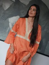 Vestido color naranja de lino con escote en V y mangas anchas.