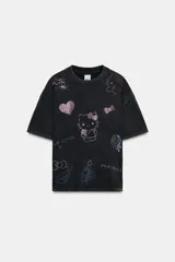 Camiseta de algodón con efecto lavado, cuello redondo y manga corta. Presenta múltiples estampados brillantes de Hello Kitty y motivos relacionados realizados con pedrería.