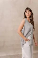 Chaleco gris de punto calado, con escote en V, sin mangas y cierre frontal con tres botones. Presenta un corte amplio y relajado con terminaciones acanaladas.