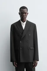 Blazer de corte regular confeccionada en tejido de lana italiana. Presenta cuello con solapas de pico, cierre frontal de botonadura cruzada, manga larga con puños abotonados, bolsillos de vivo en el pecho y bolsillos de solapa en la cadera.