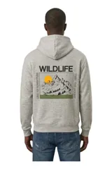Buzo canguro de felpa color gris melange, con capucha y gran estampa en la espalda con diseño de montañas, sol y la inscripción 'Wildlife'.