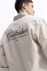 Camisa de popelina a cuadros, color celeste y blanco, de manga larga y corte holgado. Presenta un bolsillo frontal y cartera abotonada.