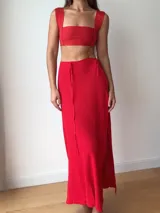 Falda larga tejida color marrón con brillo metálico, corte al cuerpo, abertura alta en la pierna y recortes laterales con cordones ajustables.