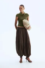 Top de punto suave verde militar, de corte ceñido, cuello alto y mangas cortas con aberturas laterales en las sisas.