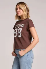 Remera marrón con estampado frontal en color blanco con la inscripción 'J'adore 98' de estilo universitario.
