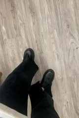 Jean negro de corte wide leg con tajo frontal y tiro medio alto.