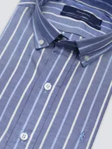 Camisa de hombre clásica de manga larga, confeccionada en 100% algodón, con diseño de rayas verticales en tonos azul, celeste y blanco, cuello abotonado y bordado sutil en el pecho.