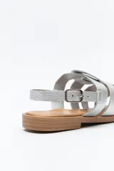 Sandalias plateadas de cuero sintético con tiras anchas cruzadas y detalle central calado. Cierre con hebilla ajustable y suela plana color suela.