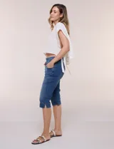 Pantalón capri de denim azul con cintura tipo faja elastizada, bolsillos frontales y traseros, y ajuste entallado por debajo de la rodilla.