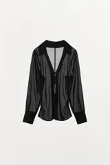 Camisa de cuello solapa con escote en pico y manga larga acabada en puño con abertura y lazo, confeccionada en tejido semitransparente de color negro con aplicación de tachas delanteras, cintura entallada con frunces laterales y cierre frontal con lazos.