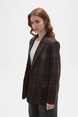 Blazer de corte holgado con diseño a cuadros en tonos marrones y negros. Presenta cuello con solapa, cierre frontal con un botón y bolsillos laterales con solapa.