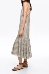 Vestido midi con estampado de cuadros vichy en tonos beige y azul, escote en V, tirantes finos ajustables con lazos en los hombros y volante fruncido en el bajo.