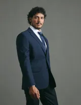 Saco de vestir azul marino con cuello solapa, manga larga y cierre frontal de dos botones. Presenta un diseño clásico con bolsillos laterales con solapa y un bolsillo superior en el pecho.