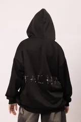 Campera oversize con capucha y cierre frontal metálico. Presenta bolsillos frontales con remaches metálicos y un diseño exclusivo en la espalda con la palabra "TACHA" formada por alfileres de gancho plateados. Confeccionada en tejido de jersey con interior suave.