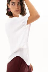 Blusa blanca de corte holgado y diseño minimalista, con mangas cortas tipo murciélago que presentan un detalle de fruncido lateral con cordón ajustable.