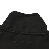 Campera polar con cierre frontal, cuello alto y diseño combinado. Presenta un panel superior liso en color negro y el resto de la prenda con un estampado de ondas en tonos verde, marrón y beige. Incluye bolsillos laterales y un parche decorativo en el pecho.