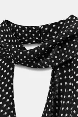 Top halter de viscosa con estampado de lunares, cuello halter, espalda descubierta y detalle de lazadas en el mismo tejido. Cuenta con bajo redondeado y cierre trasero con botones.