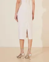 Falda midi de corte recto y tiro alto, confeccionada en tela lisa de color blanco.